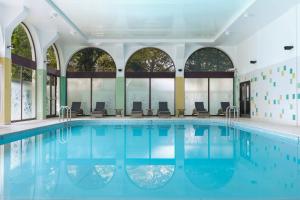 伦敦伦敦摄政公园万豪酒店的一座带椅子的游泳池,位于带窗户的建筑内