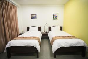 曼谷苏22号公寓的配有白色床单的酒店客房内的两张床