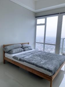 雅加达Studio Apartment at Puri Mansion West Jakarta的白色客房的一张床铺,设有大窗户