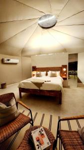 BadīyahStarry Domes Desert Camp的一间卧室配有一张大床和两把椅子
