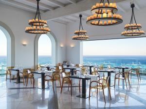 法里拉基Esperos Village Blue & Spa - Adults Only的用餐室配有桌椅和吊灯。