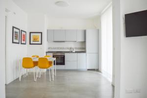 皮内托Homiday - Residenza Caravelle的白色的厨房配有桌子和黄色椅子