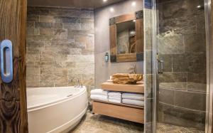 夏蒙尼-勃朗峰Les Grands Montets Hotel & Spa的带浴缸和玻璃淋浴间的浴室。