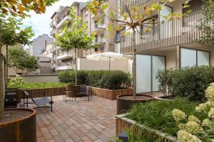 卢森堡The Central City - Luxury ApartHotel的庭院设有桌椅,树木和建筑