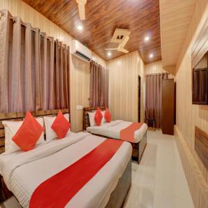 阿利鲍格Hotel Snehaprabha - Near to Nagaon Beach Alibaug的一间卧室配有两张带红色枕头的床