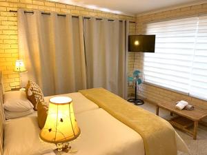 肯普顿帕克Safari Club Guest Lodge OR Tambo International Airport的一间卧室设有一张床、一台电视和一个窗口。