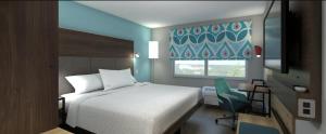 威尔明顿Tru By Hilton Wilmington的卧室配有床、椅子和窗户。