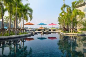苏林海滩普吉島美達格蘭德渡假村的一个带遮阳伞和椅子的游泳池以及棕榈树