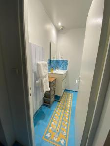 图勒L'Escale ZEN的设有带水槽的浴室,铺有蓝色和黄色的地板。