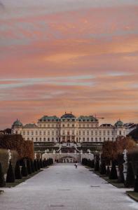 维也纳HENRI Hotel Wien Siebterbezirk的一座白色的大建筑,背面有日落