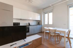米兰YouHosty - Del Castagno 2的厨房配有白色橱柜和桌椅