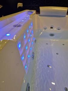 Suite Coquine avec jacuzzi YaoSpa60的白色浴缸,上面有蓝色的灯光