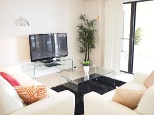 凯恩斯凯恩斯边缘公寓式酒店的客厅配有白色家具和平面电视