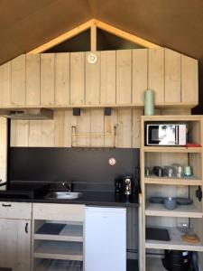 卡兰茨奥赫Safari Lodge, glamping aan zee!的厨房配有木制橱柜、水槽和微波炉