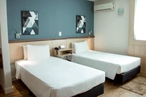 坎普斯戈伊塔卡济斯坎波斯多斯戈塔卡兹舒适酒店的两张位于酒店客房的床,拥有蓝色的墙壁