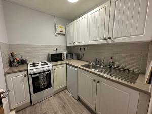 吉斯伯勒Cosy, 2 Bedroom Cottage in Guisborough Town Centre的厨房配有白色橱柜、水槽和炉灶。