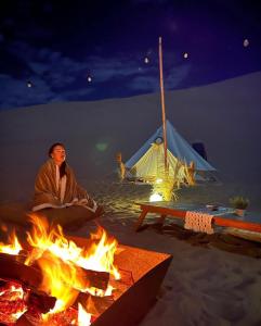 伊察Duna Camp Huacachina的坐在火上,背靠帐篷的人