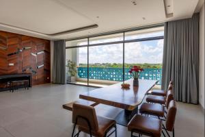 Gò CôngThe Stay Saigon Riverfront的一间带桌椅和大窗户的用餐室