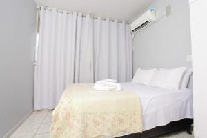 戈亚尼亚Apartamento confortável的一间卧室配有一张带白色床单的床和一扇窗户。