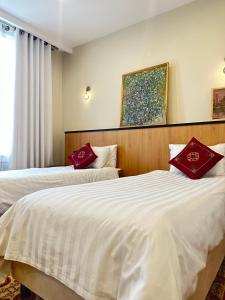 努库斯吉佩克漂亮酒店的两张位于酒店客房的床铺,配有红色枕头