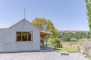 特卡波湖Mount Cook Station Shearers Quarters Lodge的一间设有红色窗户和野餐桌的小房子