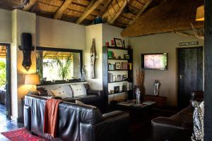 巴卢莱自然保护区恩祖韦尼野味旅舍的客厅配有真皮沙发和桌子