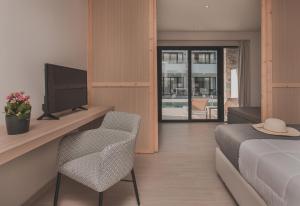 卡拉马孔Cavo di Suites的一间卧室配有一张床、一台电视和一把椅子