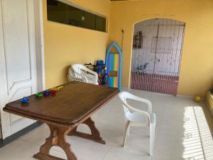 贝伦Casa de praia no Ariramba, Mosqueiro, Belém/PA.的一间带木桌和白色椅子的用餐室