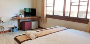 美塞NAVY HOME HOTEL โรงแรมเนวี่โฮม的一间卧室配有一张带书桌和电视的床。