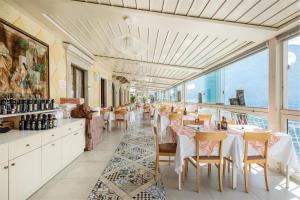 利莫内-苏尔加达Hotel Le Palme的餐厅设有白色的桌椅和窗户。