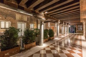 威尼斯Palazzo Morosini Degli Spezieri - Apartments的一座种植盆栽植物的古老建筑中的拱廊