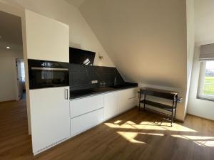 ZoutleeuwVakantieappartement Logies Terhagen的厨房配有白色橱柜和黑色台面