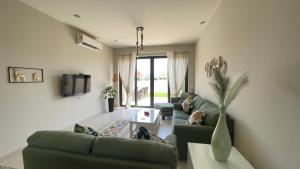 赫尔格达Luxury 3BR Townhouse, Tawila, El Gouna, Lagoon & Pool access的客厅配有绿色沙发和电视