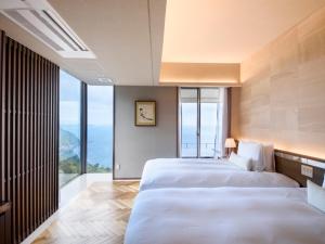 热海Atami Sekaie的配有大窗户的酒店客房内的两张床