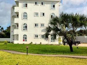 马林迪PahaliMzuri Kijani - 1 Bedroom Beach Apartment with Swimming Pool的一座白色的大建筑,前面有一棵棕榈树