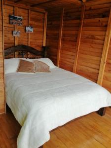 瓜塔维塔Cabañas Guatavita的木墙客房的一张床位