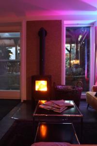 施利茨The Birdy Mountains Luxury Lodge 2的带壁炉的客厅配有紫色照明