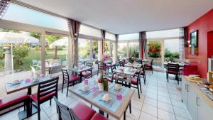 埃维昂莱班法兰西康塔克酒店的用餐室设有桌椅和窗户。