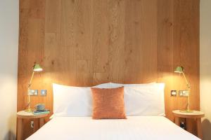 爱丁堡Cairn Hotel & Apartments的一张带木制床头板和两盏灯的床