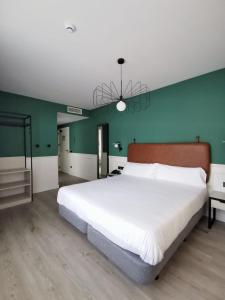 帕伦西亚唐罗德里戈酒店的卧室设有一张白色大床和绿色的墙壁