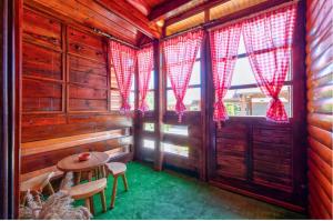 兹拉蒂博尔Zlatibor Brvnare Zakos的一间设有红色窗帘和一张桌子的小屋