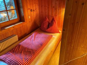 施图拜河谷新施蒂夫特Ferienhaus Falbeson的小屋配有两个红色和白色的枕头,位于长凳上