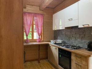 普利特维采湖Wooden house with a waterfall "Stipanov mlin"的厨房配有白色橱柜、炉灶和窗户。