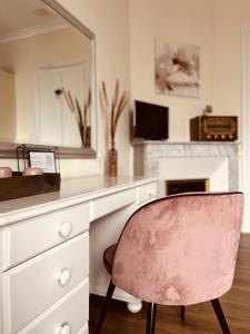 勒法韦La Maison de Louisette的一张粉红色的椅子,坐在一张桌子前,带镜子