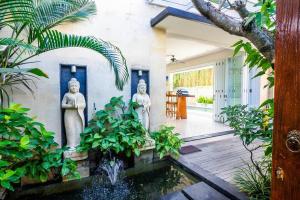 勒吉安Villa Lacasa3 -Modern tropical 3BR Villa with butler的两座雕像,位于一座带池塘的房屋的庭院内