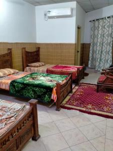 拉合尔Five Giants Lahore Homestay的一间设有三张床和三块地毯的房间