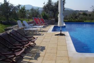 圣温琴佐Villa Belvedere的游泳池旁的天井配有椅子和遮阳伞。