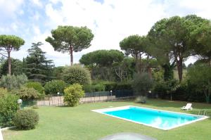 拉斯图塔Vacanze Romane Olgiata的一座树木繁茂的庭院内的游泳池