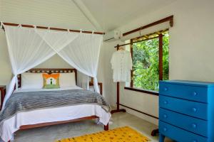 托兰克索Casa Laranjeiras, Rio da Barra beach, Trancoso的一间卧室配有天蓬床和蓝色梳妆台
