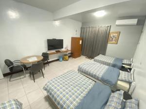 Changhua County彰濱伸港民宿的客房设有两张床、一张桌子和电视。